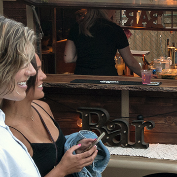 Women smiling being served drinks from a mobile bar