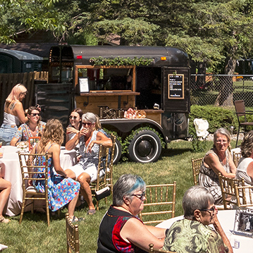 Group of people enjoying drinks outdoors with vintage mobile box bar